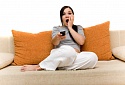 Girl sitting on sofa watching TV, shocked